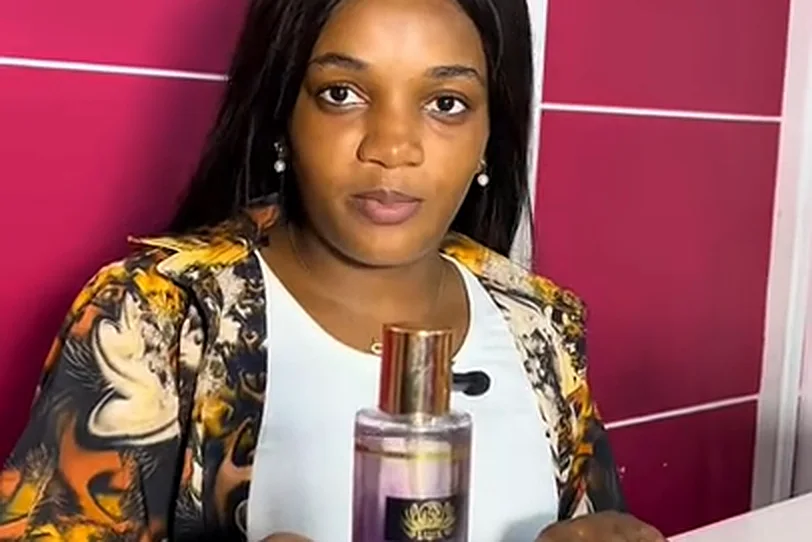 Ruth Ornella, manager of MOS MARKET, at the till holding one of her fragrances